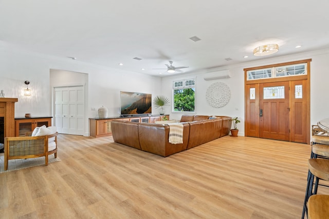 living room with light hardwood / wood-style flooring, a wall mounted AC, crown molding, and ceiling fan