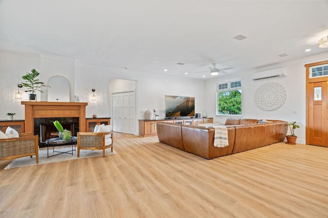 living room featuring a fireplace, light hardwood / wood-style floors, crown molding, and a wall mounted AC