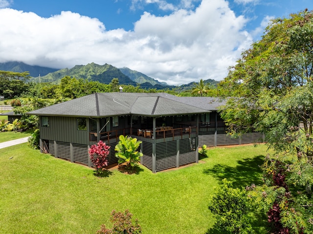 rear view of property featuring a deck with mountain view and a lawn