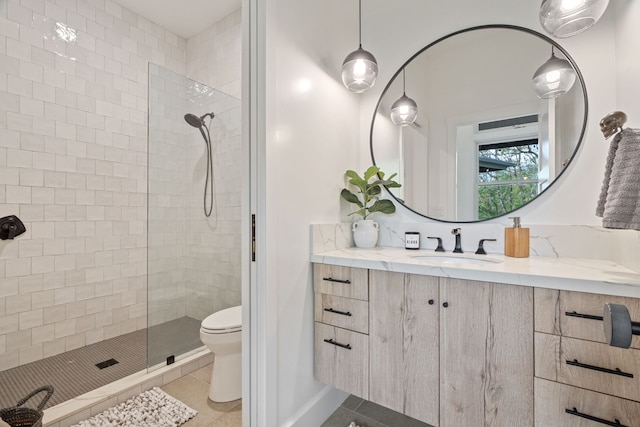 bathroom with tiled shower, tile patterned flooring, vanity, and toilet