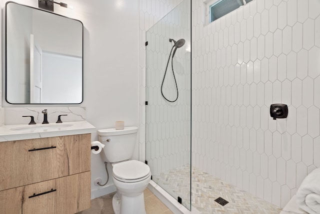 bathroom with tile patterned floors, vanity, toilet, and tiled shower