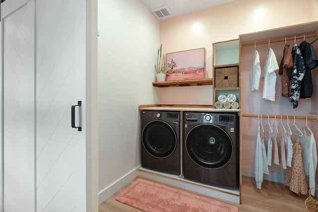 laundry room featuring washing machine and dryer and light hardwood / wood-style floors