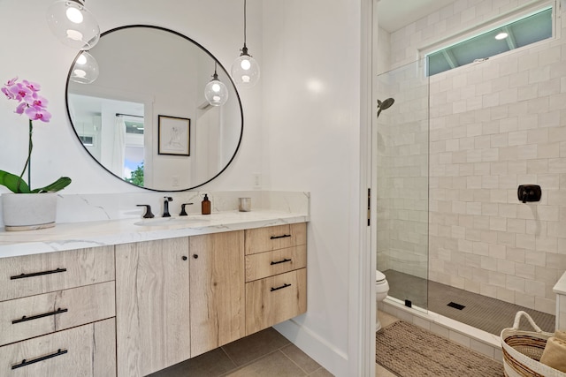 bathroom with tile patterned flooring, vanity, toilet, and tiled shower