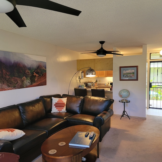 living room with a textured ceiling, ceiling fan, and light colored carpet