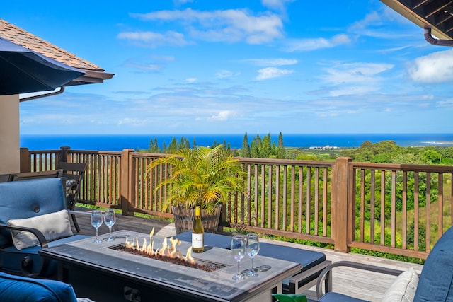 wooden terrace with a water view and a fire pit