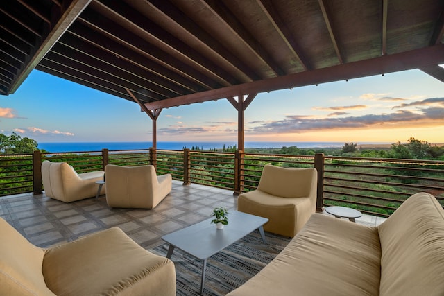 patio terrace at dusk with a balcony, a water view, and an outdoor hangout area