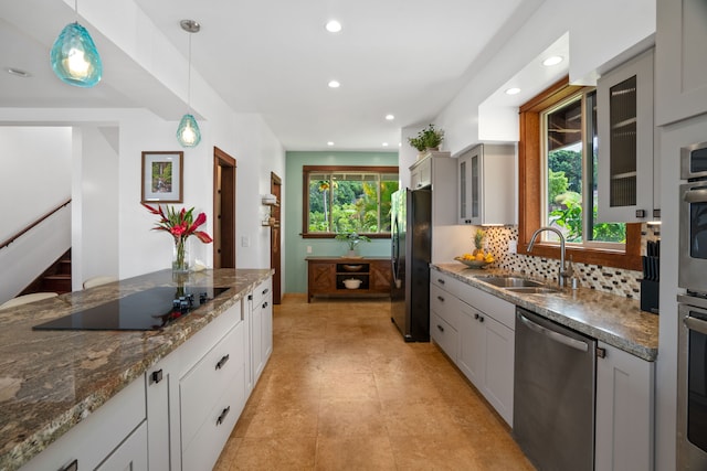 kitchen featuring hanging light fixtures, sink, gray cabinets, dark stone countertops, and black appliances