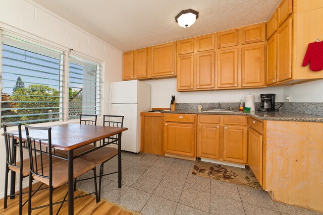 kitchen featuring white fridge, light hardwood / wood-style flooring, sink, and a textured ceiling