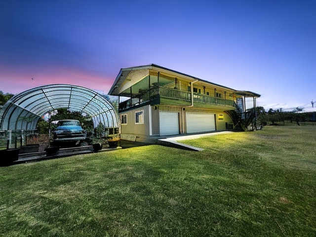 exterior space featuring a balcony, a garage, and a lawn