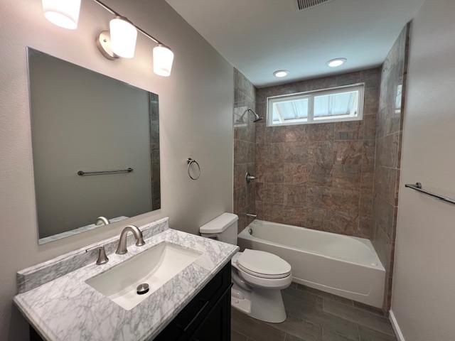 full bathroom featuring toilet, tiled shower / bath combo, and vanity