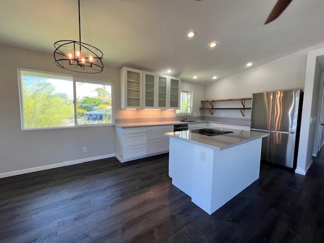 kitchen with pendant lighting, a center island, stainless steel refrigerator, white cabinetry, and black electric cooktop