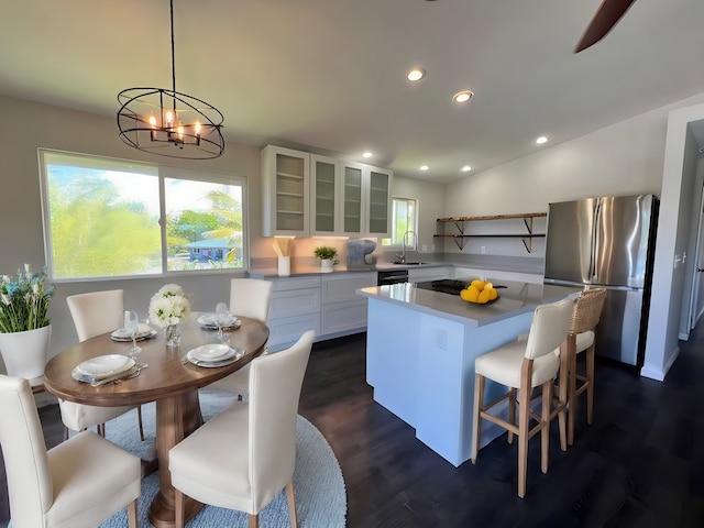 kitchen with pendant lighting, a kitchen island, white cabinetry, plenty of natural light, and stainless steel fridge