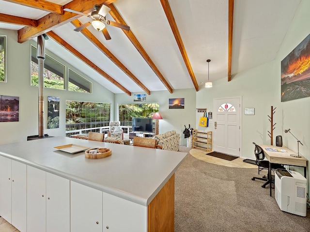 kitchen with white cabinetry, pendant lighting, light colored carpet, and beamed ceiling