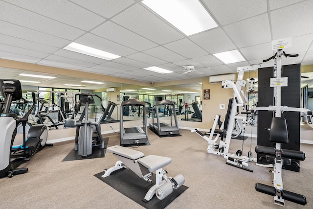 gym featuring a paneled ceiling, a wall unit AC, and carpet flooring