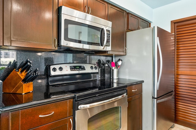 kitchen with stainless steel appliances, decorative backsplash, and dark stone countertops