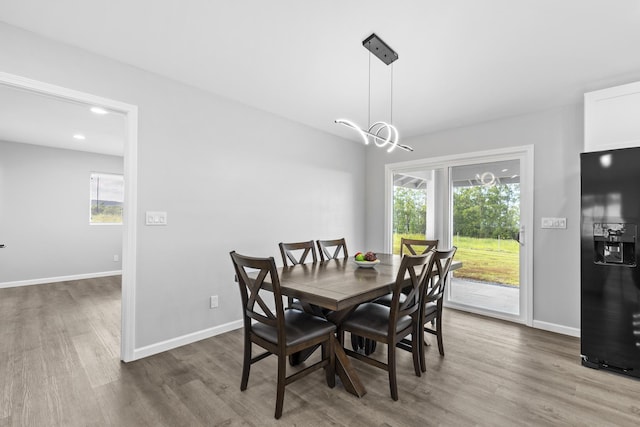 dining space with wood-type flooring, plenty of natural light, and a notable chandelier