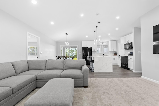 carpeted living room featuring lofted ceiling and sink