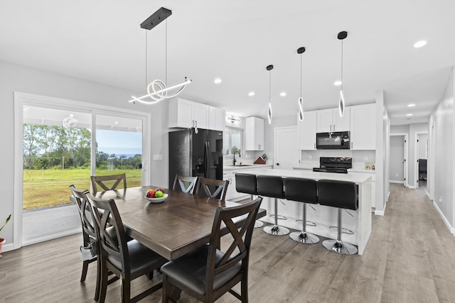 dining room with lofted ceiling, a healthy amount of sunlight, sink, and light hardwood / wood-style floors