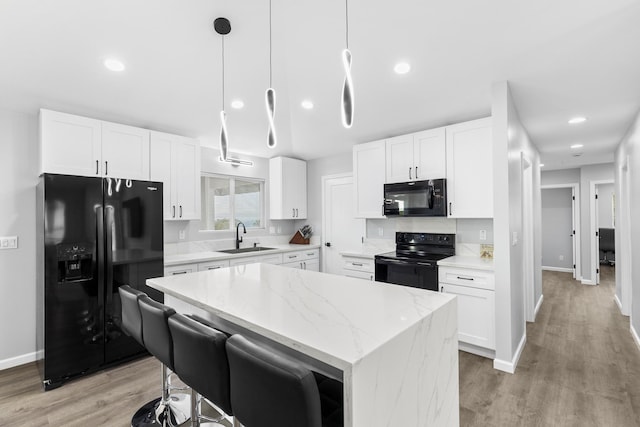 kitchen with sink, black appliances, a kitchen island, pendant lighting, and white cabinets