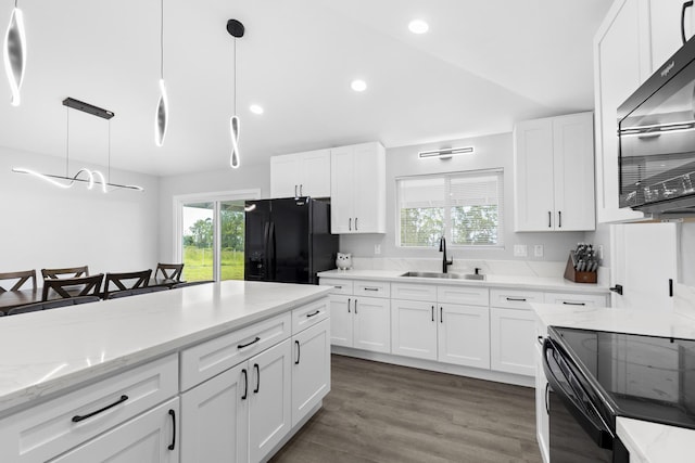 kitchen with sink, light stone counters, decorative light fixtures, black appliances, and white cabinets