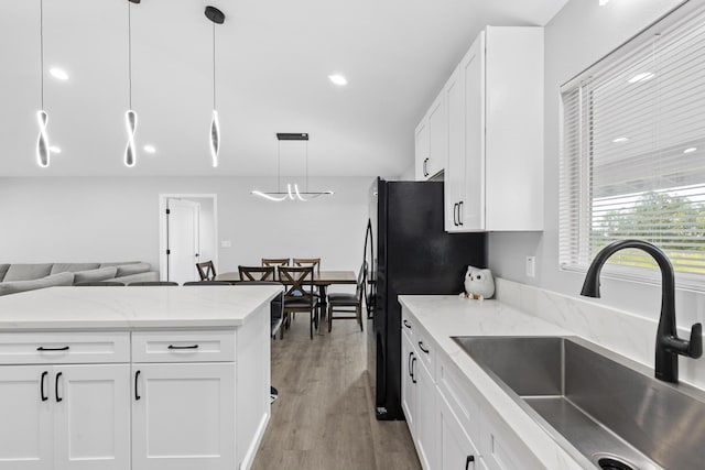 kitchen featuring sink, light stone counters, decorative light fixtures, light wood-type flooring, and white cabinets