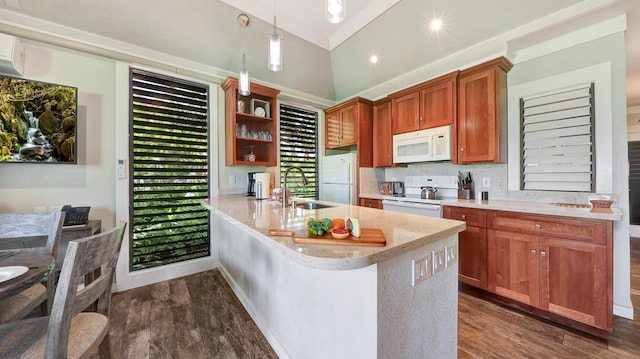 kitchen with a breakfast bar, white appliances, hanging light fixtures, dark hardwood / wood-style floors, and kitchen peninsula