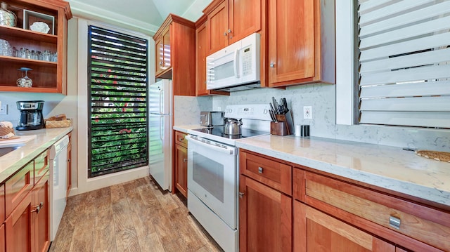 kitchen featuring decorative backsplash, light stone countertops, white appliances, and light wood-type flooring