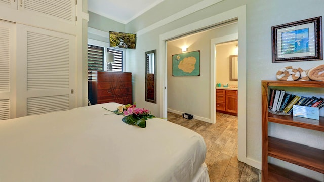 bedroom with light hardwood / wood-style floors, ensuite bath, and a closet