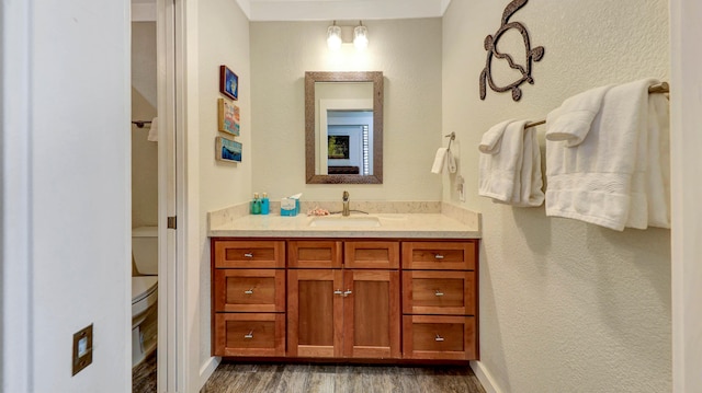 bathroom with hardwood / wood-style floors, vanity, and toilet