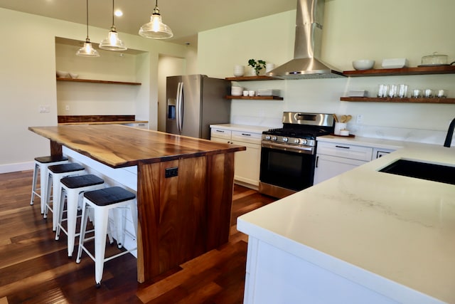 kitchen featuring wall chimney range hood, dark wood-type flooring, white cabinetry, appliances with stainless steel finishes, and sink