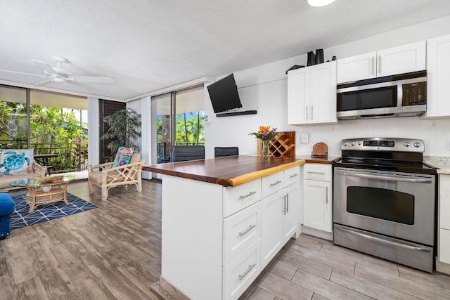 kitchen featuring white cabinets, appliances with stainless steel finishes, wood counters, and a textured ceiling