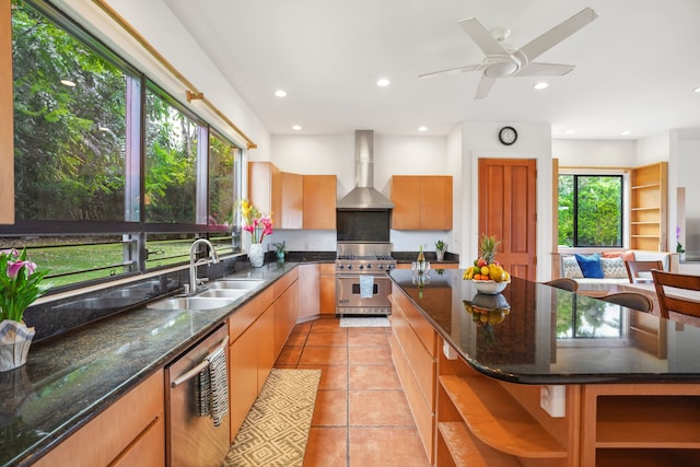 kitchen featuring wall chimney range hood, appliances with stainless steel finishes, a center island, and light tile patterned floors