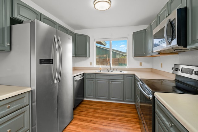 kitchen featuring appliances with stainless steel finishes, light hardwood / wood-style flooring, and sink