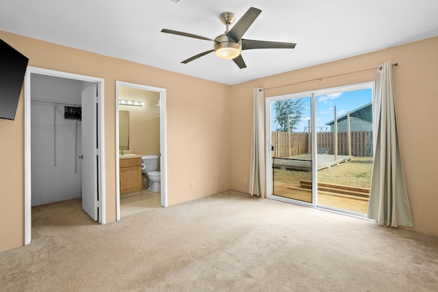 unfurnished bedroom featuring ceiling fan, light colored carpet, access to exterior, and ensuite bath