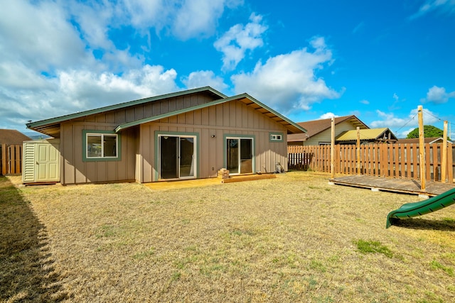 back of house featuring a playground, a yard, and a shed