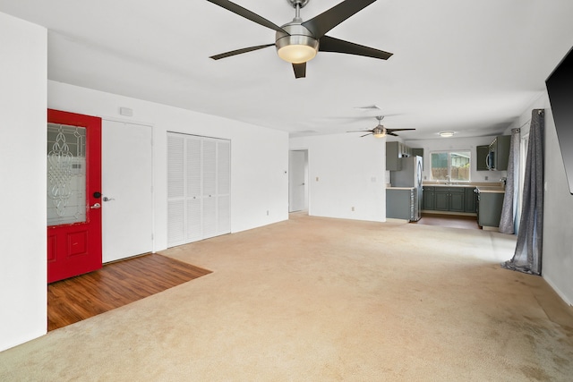 unfurnished living room with dark carpet and ceiling fan