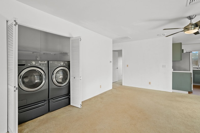 clothes washing area featuring light carpet, washing machine and dryer, and ceiling fan