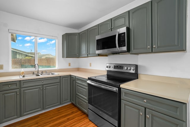 kitchen featuring gray cabinetry, dark wood-type flooring, stainless steel appliances, and sink