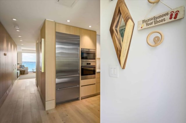 kitchen featuring light hardwood / wood-style floors, a water view, light brown cabinets, and appliances with stainless steel finishes