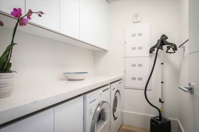 clothes washing area featuring washing machine and clothes dryer and cabinets