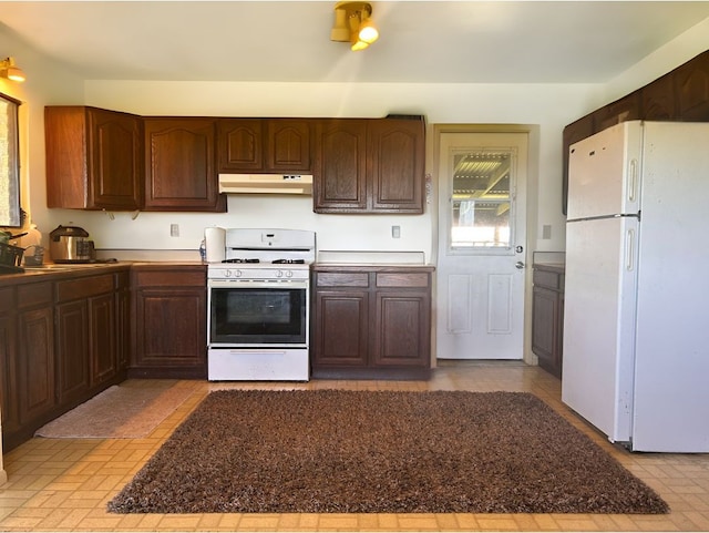 kitchen featuring dark brown cabinetry and white appliances