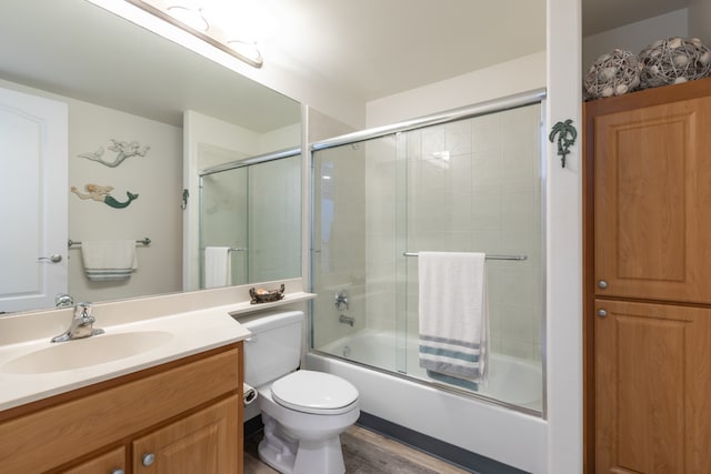 full bathroom with vanity, wood-type flooring, toilet, and bath / shower combo with glass door