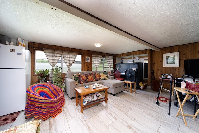 living room with beam ceiling, a textured ceiling, and wood walls