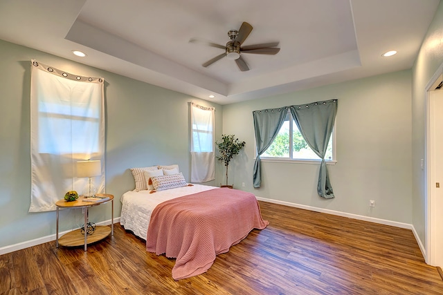 bedroom featuring ceiling fan, a raised ceiling, and hardwood / wood-style flooring