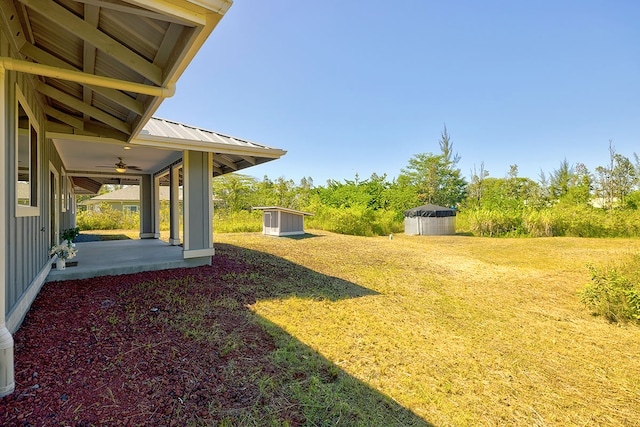 view of yard with ceiling fan, a patio, and a storage unit