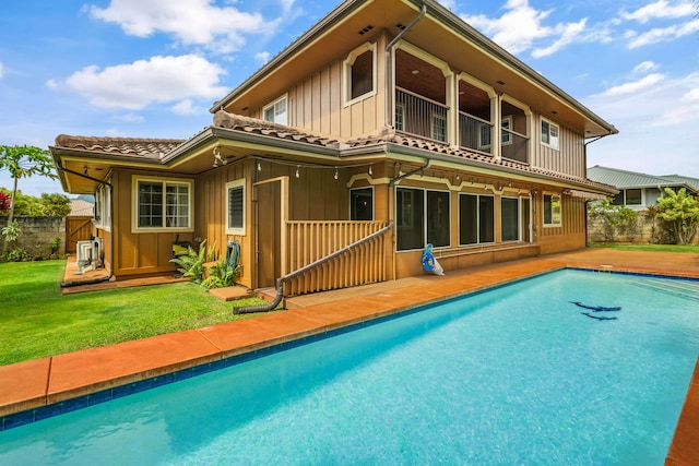 rear view of house with a balcony and a fenced in pool