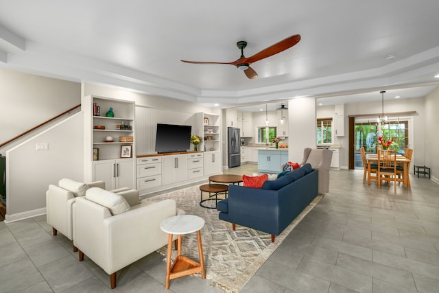 living room featuring ceiling fan, a raised ceiling, light tile patterned floors, and built in features