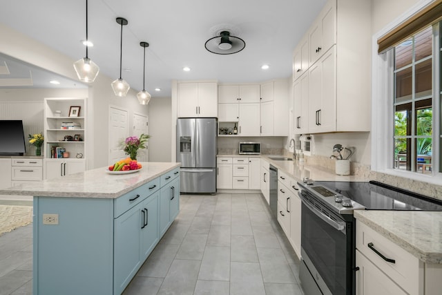 kitchen with sink, decorative light fixtures, light stone countertops, white cabinetry, and stainless steel appliances