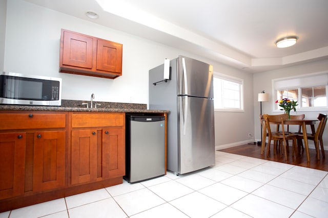 kitchen with sink, dark stone counters, appliances with stainless steel finishes, and light hardwood / wood-style floors