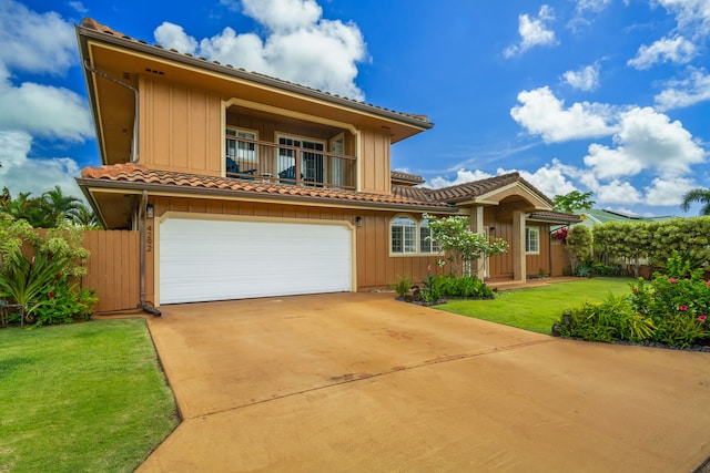 view of front of home featuring a balcony, a front yard, and a garage